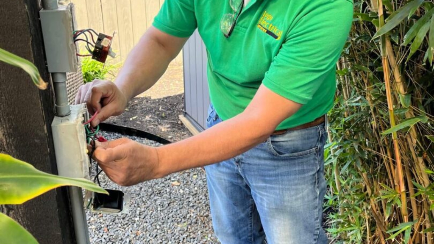 Electrician working on outdoor electrical box.