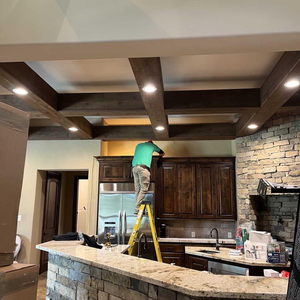 Worker installing kitchen cabinets on ladder.