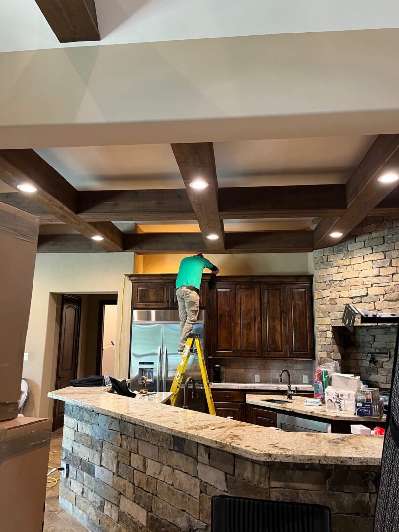 Worker installing kitchen cabinets on ladder.