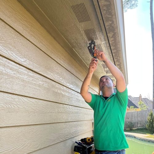 Technician installing outdoor lighting fixture.